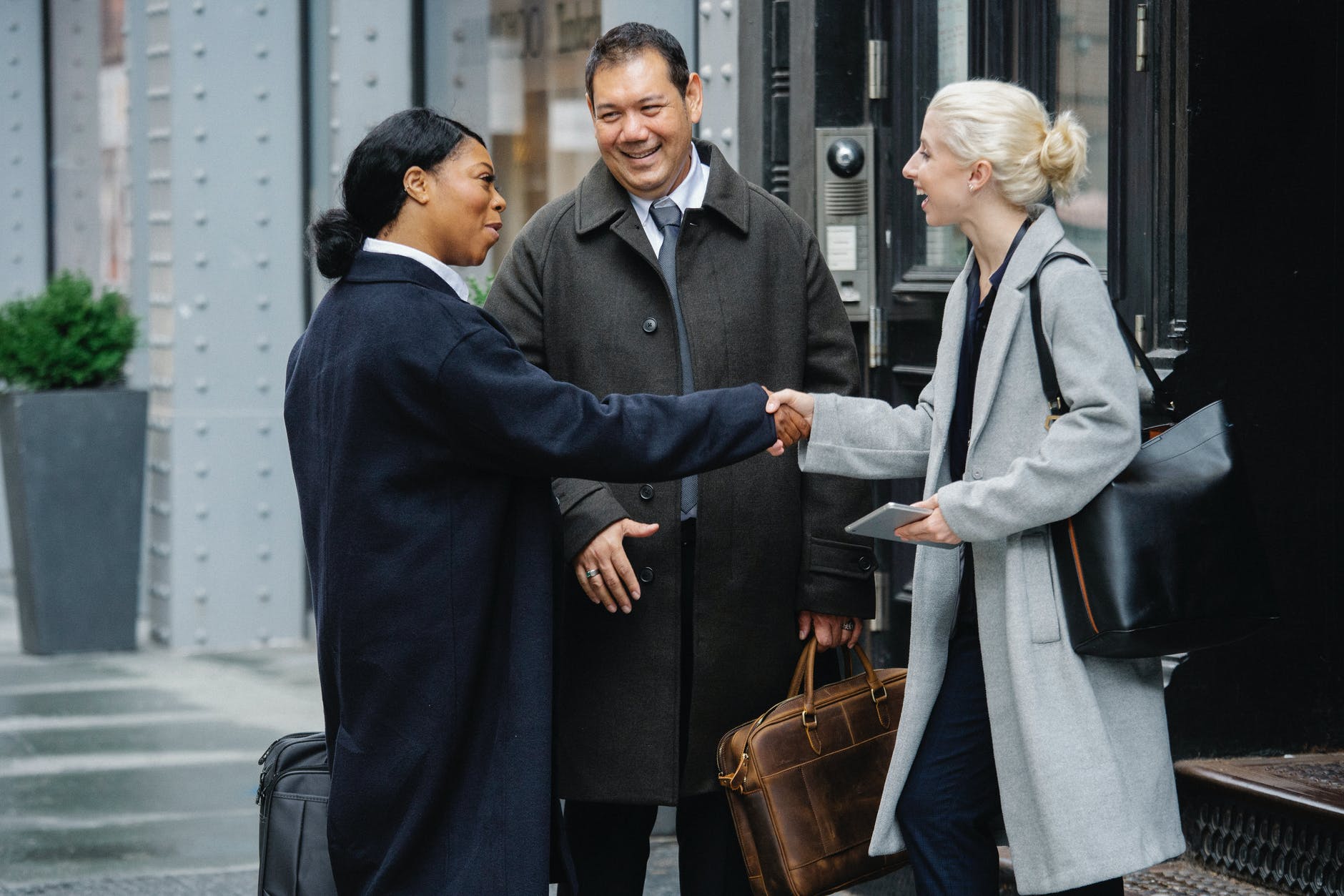 Three businesspeople shaking hands outdoors.