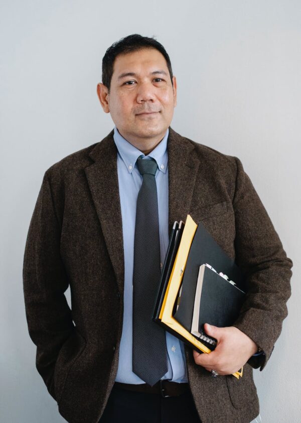 glad asian businessman standing with documents in hand in office