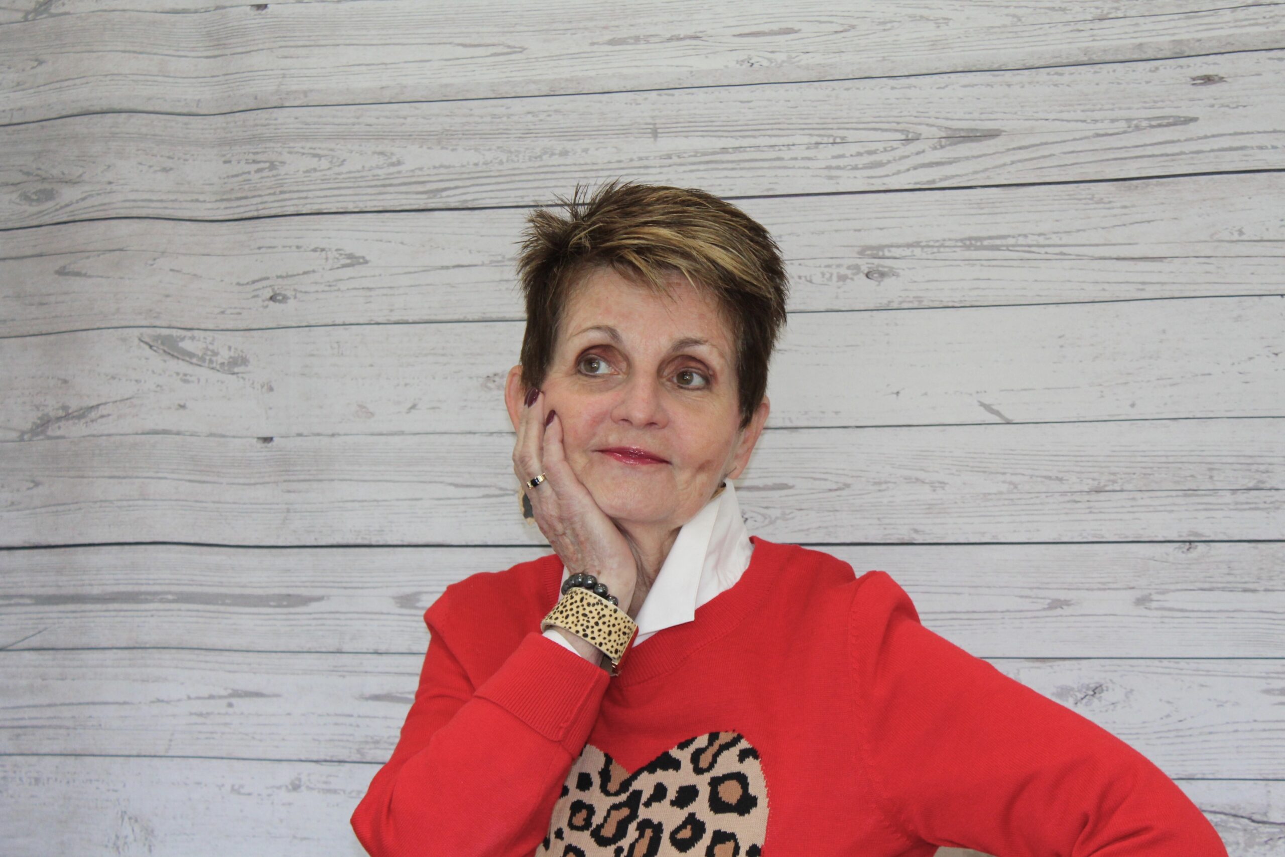 A woman in red sweater with leopard print shirt and bracelet.